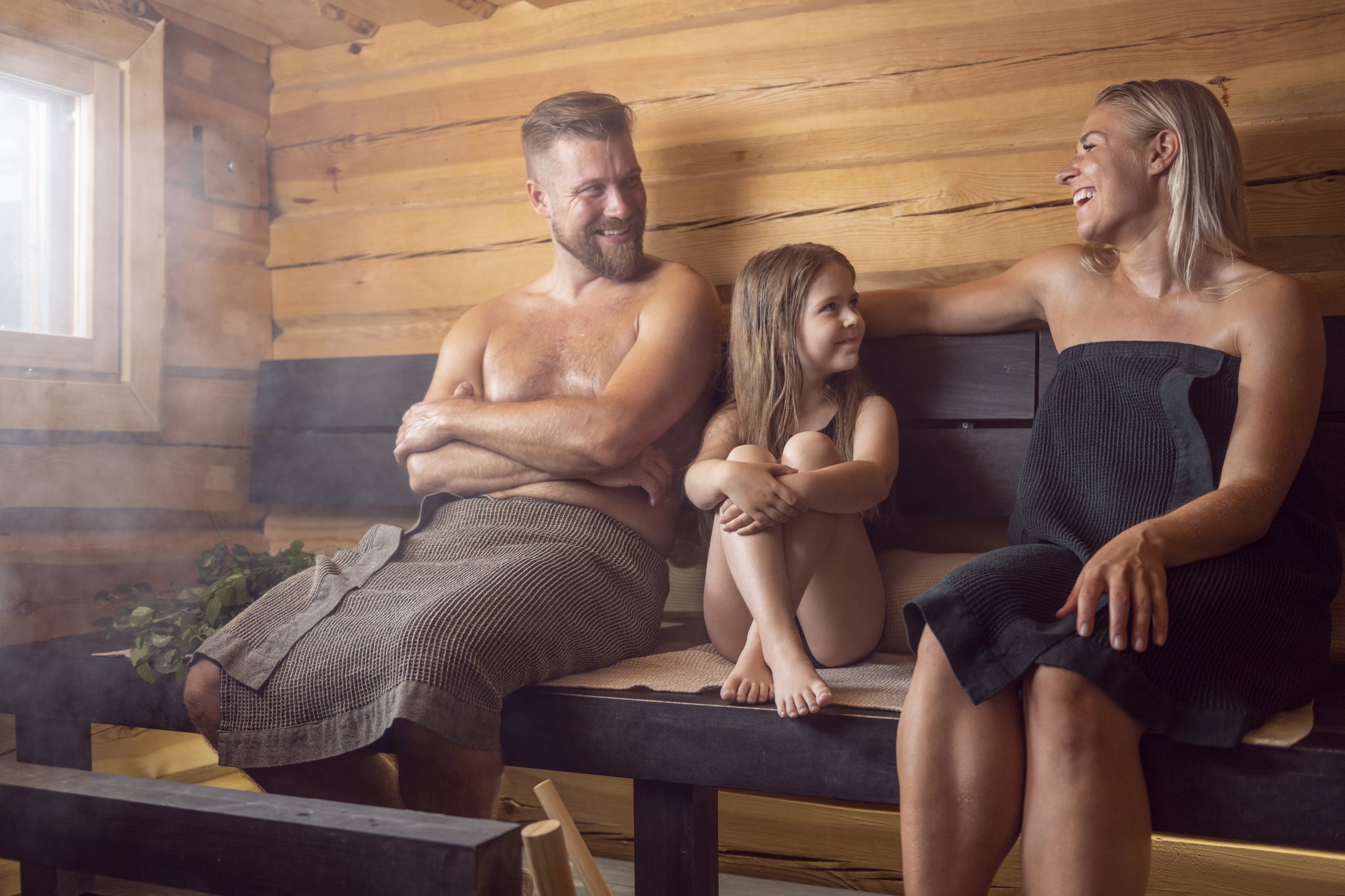Perhe saunoo mökkisaunassa. A Family barthin in summer cottage sauna.